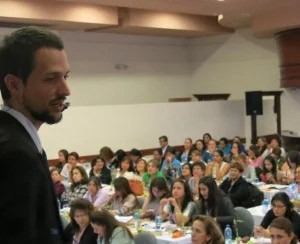 Sobre mí - Consultor SEO con foco en crecimiento de negocio 1 el consultor seo edu campillo con traje y micro de auricular dando una conferencia en una sala con muchas personas